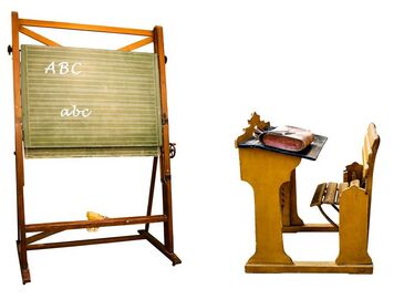 Tableau avec les lettres A B C écrites à la crée et une table d'écolier devant